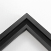 This simplistic yet modular matte black frame is designed for metal prints, acrylic prints and dry mounts. This smart design features a minimalist stepped profile that serves as a floater frame or a standard picture frame.
For the floating effect, the print can be attached on top of the inner step of the frame, without sacrificing the artwork edges.
This frame can also be used as standard picture frame. The lowered center paired with slightly raised outer lip creates a frame within a frame effect. However, due to the inner most lip of the frame, a fraction of the artwork will be hidden. But, this can be avoided with a linen liner combo.